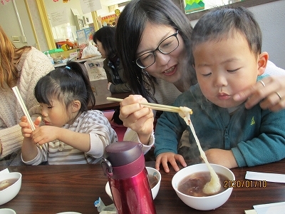 母親が男の子におもちを食べさせている様子の写真