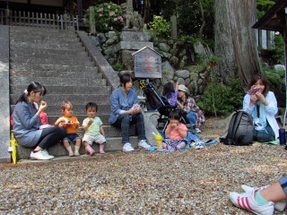 石の階段に座り親子がおにぎりを食べている写真
