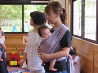 伸縮性のある布で赤ちゃんを抱っこしている母親の写真