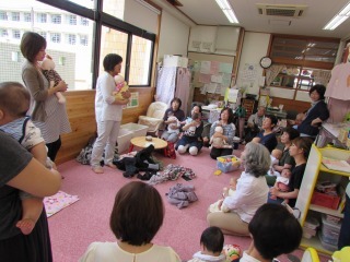 親子が座って、中央に立っている女性の話を聴いている写真