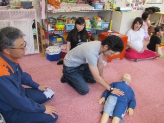 男性が幼児用人形を使って心肺蘇生の練習をしている写真