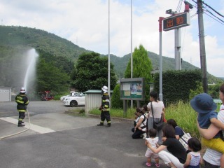 消防士が放水をしている様子を親子が見学している写真