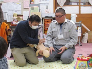 赤ちゃんの人形を使って救急法を学んでいる男性の写真