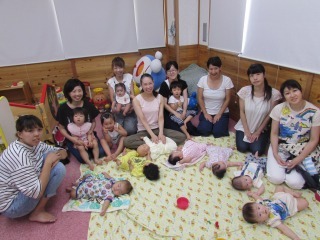 講師と参加者が寝転んでいる赤ちゃんを囲むように座り集合している記念写真