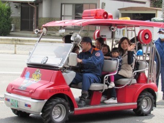 ミニ消防車に母親と子どもが乗っている写真